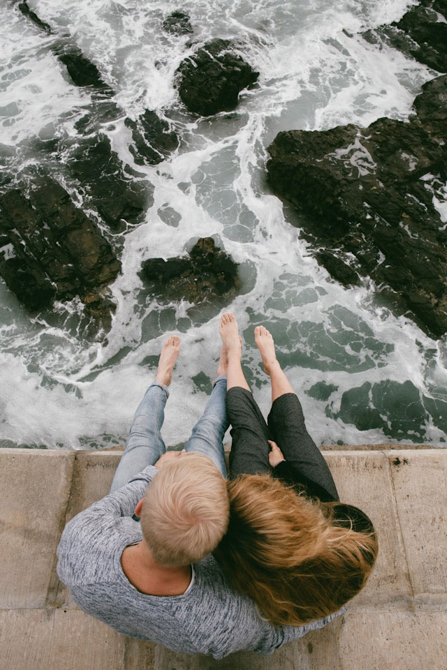 Couple overlooking waves splashing on rocks